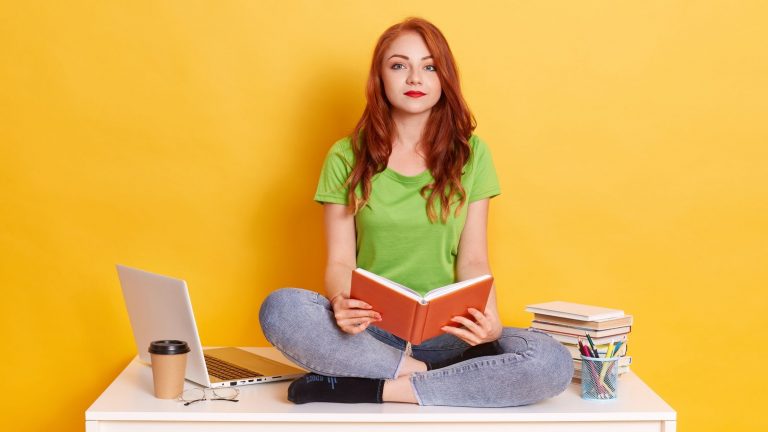a girl wearing green top holding a book